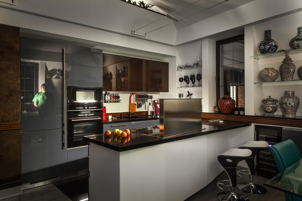 This is an example of a mid-sized industrial u-shaped open plan kitchen in Moscow with an undermount sink, glass-front cabinets, white splashback, black appliances, porcelain floors, black floor, blue cabinets, quartzite benchtops and a peninsula.