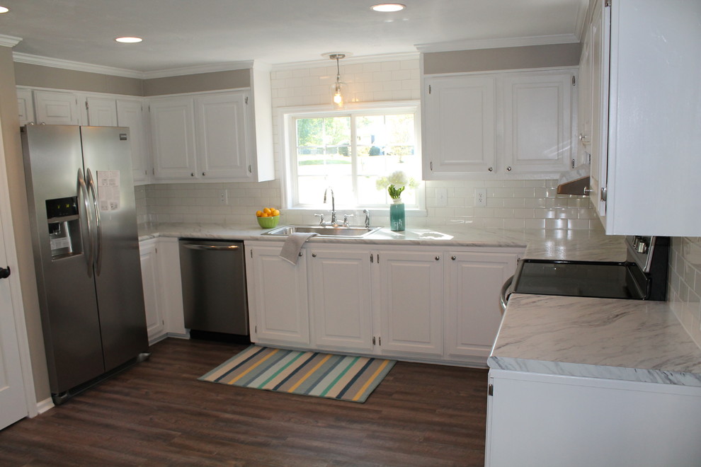 Enclosed kitchen - mid-sized craftsman u-shaped dark wood floor enclosed kitchen idea with a drop-in sink, raised-panel cabinets, white cabinets, laminate countertops, white backsplash, subway tile backsplash, stainless steel appliances and no island