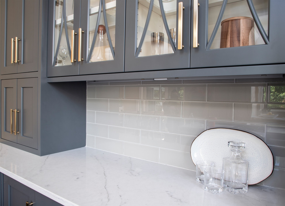 Example of a large transitional u-shaped medium tone wood floor kitchen design with an undermount sink, gray cabinets, quartz countertops, gray backsplash, glass tile backsplash, stainless steel appliances, an island and white countertops