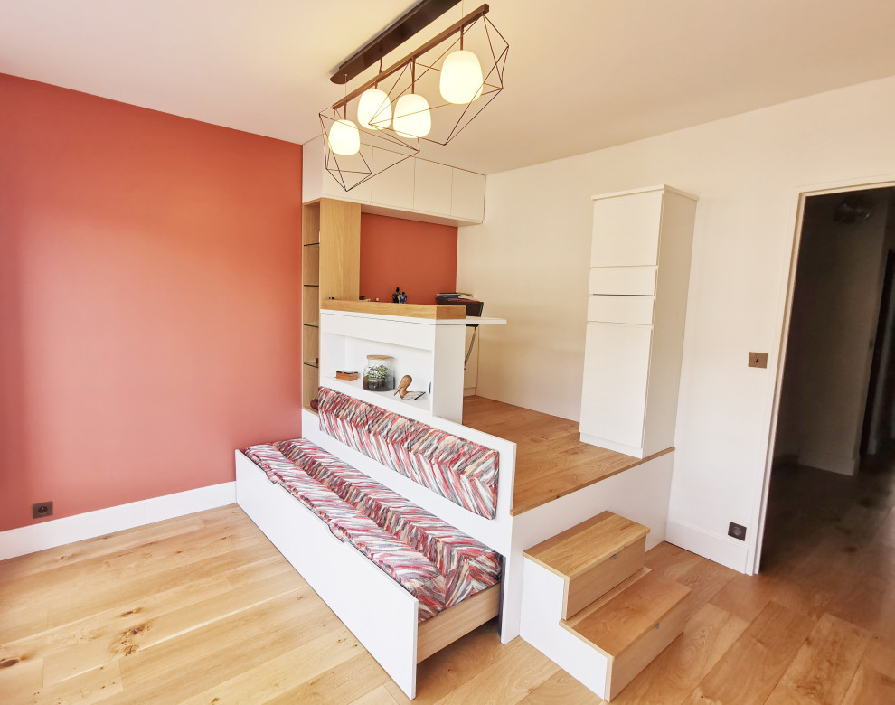 Modelo de habitación de invitados moderna grande sin chimenea con parades naranjas, suelo de madera clara y suelo marrón