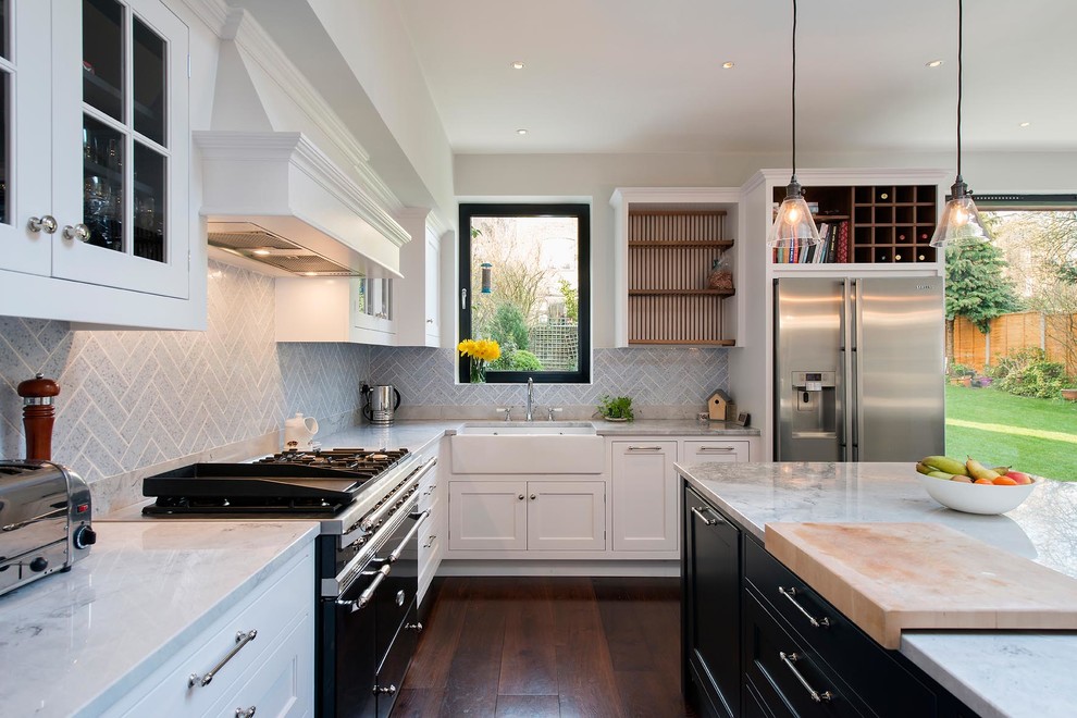 Large contemporary l-shaped eat-in kitchen in London with a farmhouse sink, recessed-panel cabinets, white cabinets, marble benchtops, grey splashback, black appliances, dark hardwood floors and with island.
