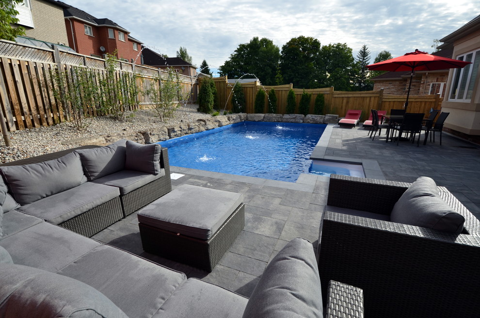 This is an example of a modern backyard rectangular pool in Toronto with a water feature and concrete pavers.