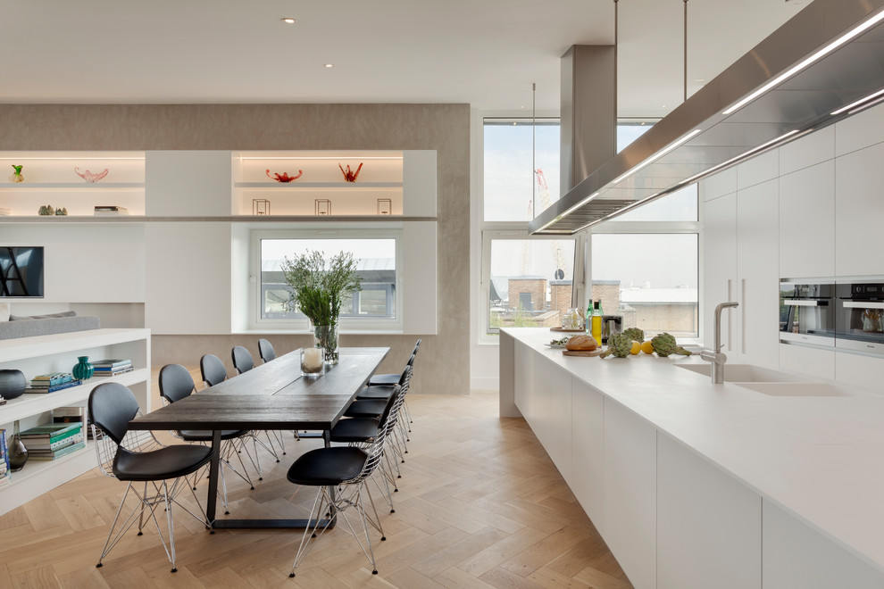 Photo of a large modern open plan kitchen in London with a double-bowl sink, flat-panel cabinets, white cabinets, light hardwood floors and with island.