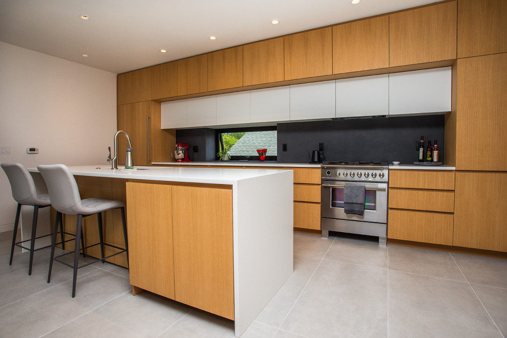 Immagine di una cucina minimalista di medie dimensioni con ante lisce, ante in legno chiaro, paraspruzzi in lastra di pietra, pavimento in cementine, top bianco, lavello da incasso, paraspruzzi nero e pavimento grigio