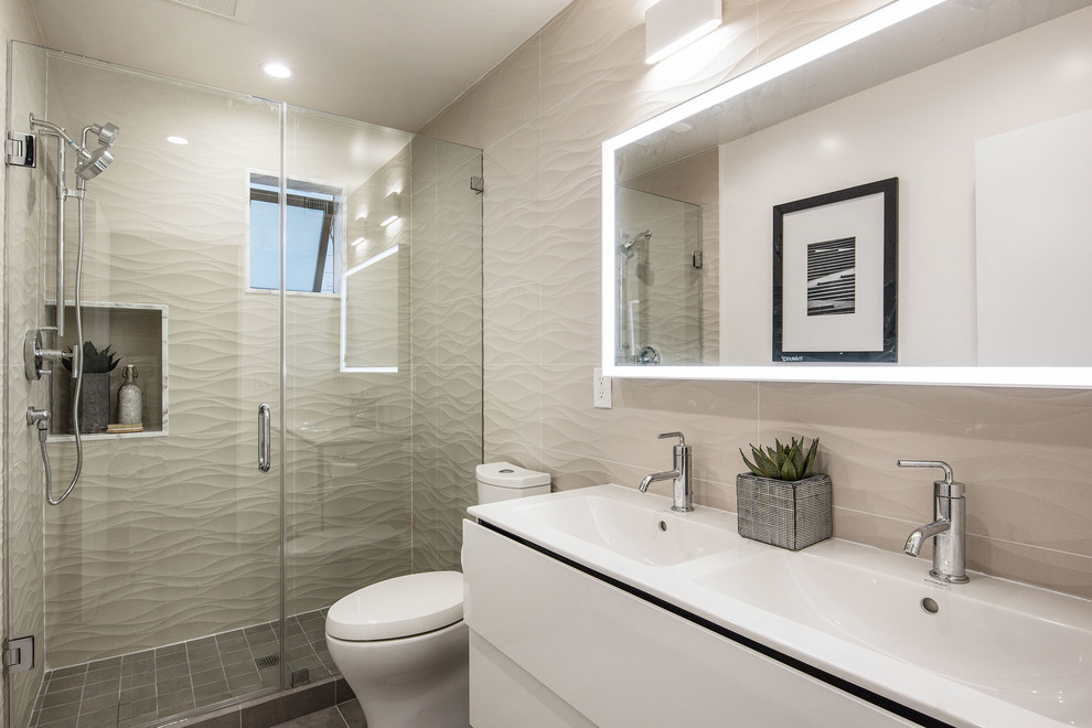 Photo of a mid-sized contemporary master bathroom in San Francisco with furniture-like cabinets, white cabinets, an alcove shower, a one-piece toilet, beige tile, ceramic tile, white walls, ceramic floors, a console sink, solid surface benchtops, grey floor, a hinged shower door and white benchtops.