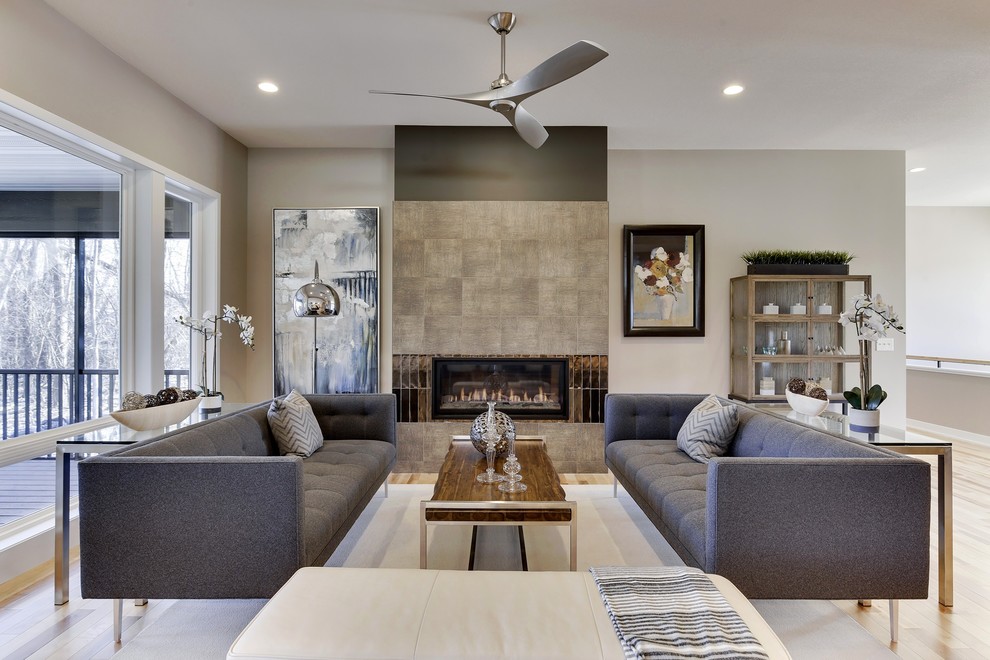 This is an example of a mid-sized contemporary open concept living room in Minneapolis with grey walls, light hardwood floors, a ribbon fireplace, a tile fireplace surround, a wall-mounted tv and beige floor.