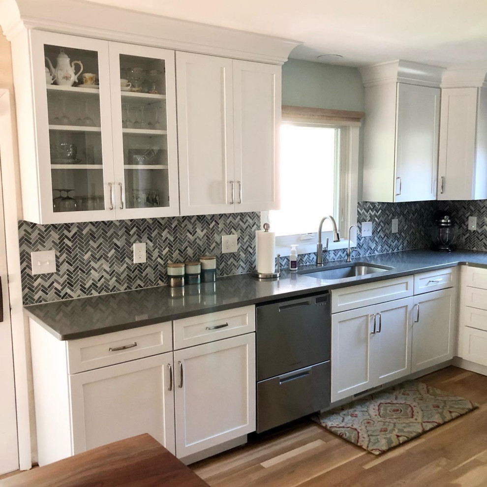 Small classic u-shaped kitchen/diner in Detroit with a submerged sink, shaker cabinets, white cabinets, engineered stone countertops, blue splashback, glass sheet splashback, stainless steel appliances, medium hardwood flooring, no island, brown floors and grey worktops.