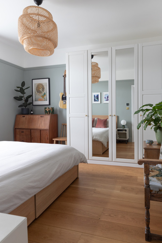 Esempio di una camera degli ospiti design di medie dimensioni con pareti verdi, pavimento in legno massello medio e pavimento marrone