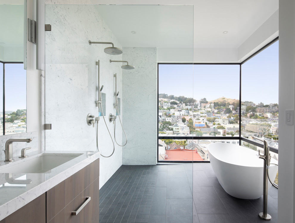 This is an example of a contemporary bathroom in San Francisco with flat-panel cabinets, dark wood cabinets, a freestanding tub, an undermount sink, black floor and white benchtops.