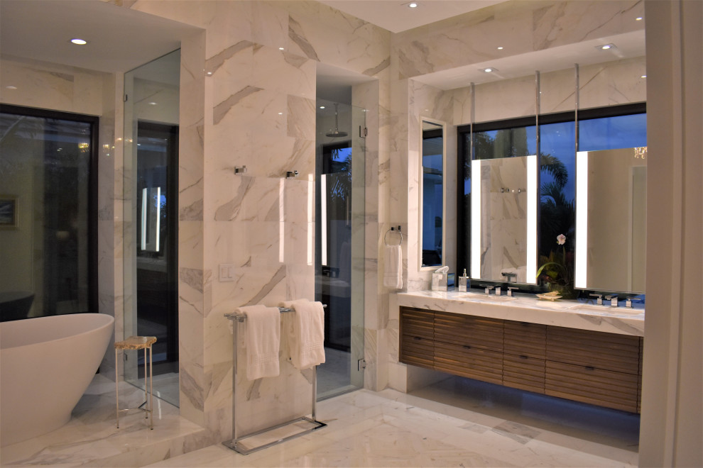 Идея дизайна: главная ванная комната среднего размера в современном стиле с фасадами с выступающей филенкой, фасадами цвета дерева среднего тона, отдельно стоящей ванной, двойным душем, раздельным унитазом, белой плиткой, мраморной плиткой, серыми стенами, мраморным полом, врезной раковиной, мраморной столешницей, белым полом, душем с распашными дверями, белой столешницей, нишей, тумбой под две раковины, подвесной тумбой и многоуровневым потолком