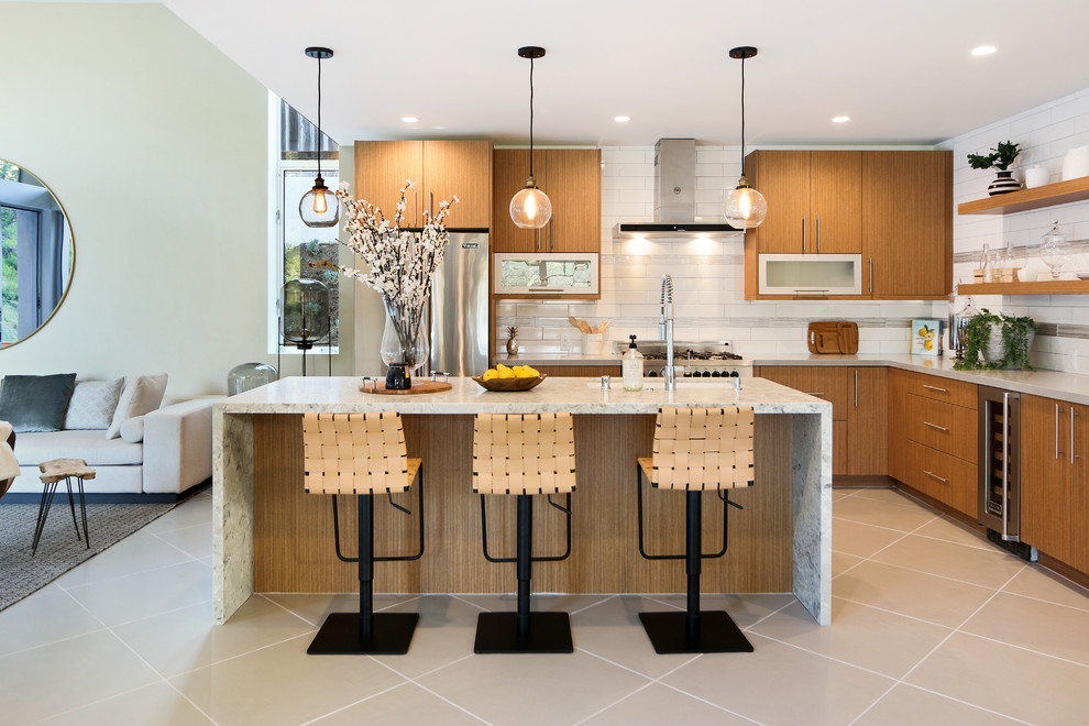 Design ideas for an expansive contemporary l-shaped open plan kitchen in Los Angeles with an undermount sink, flat-panel cabinets, medium wood cabinets, white splashback, stainless steel appliances, with island and grey floor.
