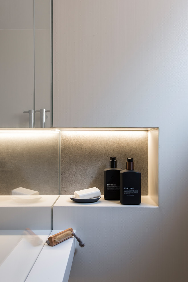 Small contemporary master bathroom in Sydney with an open shower, a wall-mount toilet, beige tile, cement tile, white walls, cement tiles, a wall-mount sink, solid surface benchtops, grey floor and an open shower.