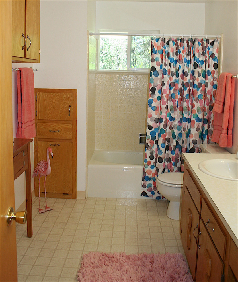 Inspiration for a mid-sized eclectic bathroom in Other with raised-panel cabinets, medium wood cabinets, a drop-in tub, a shower/bathtub combo, a two-piece toilet, yellow tile, ceramic tile, white walls, vinyl floors, a drop-in sink, laminate benchtops, yellow floor, a shower curtain, yellow benchtops, a single vanity and a built-in vanity.