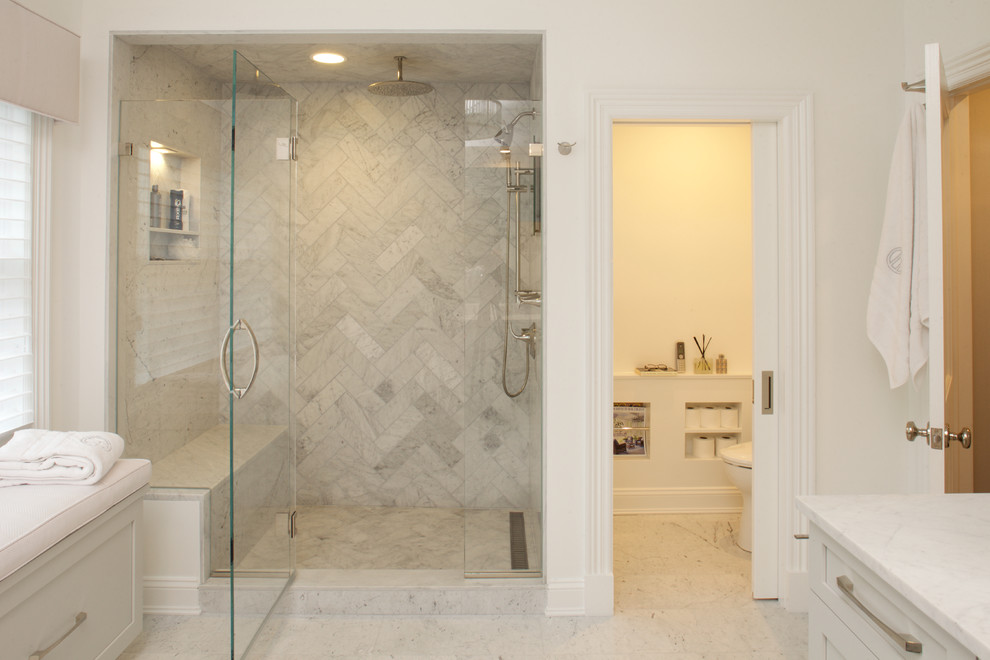 This is an example of a large transitional master bathroom in New York with shaker cabinets, white cabinets, an alcove shower, a one-piece toilet, gray tile, marble, white walls, marble floors, quartzite benchtops, white floor, a hinged shower door and an enclosed toilet.
