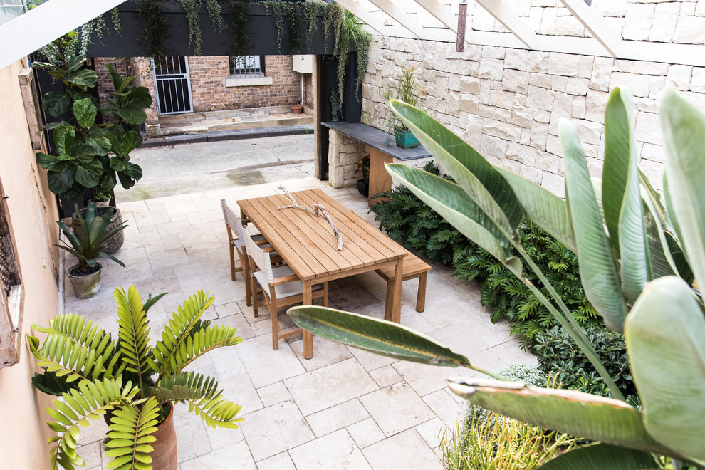 Design ideas for a small mediterranean courtyard patio in Sydney with natural stone pavers and a pergola.