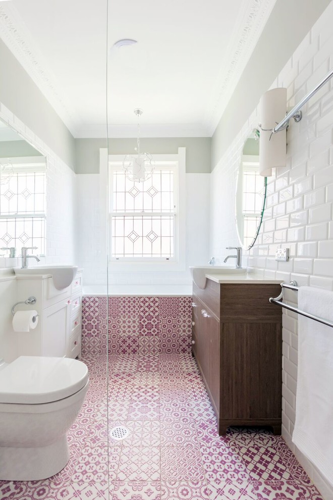 Inspiration for a small modern kids bathroom in Sydney with shaker cabinets, medium wood cabinets, a drop-in tub, a wall-mount toilet, ceramic tile, white walls, ceramic floors, engineered quartz benchtops, a corner shower, white tile, an integrated sink, pink floor and a hinged shower door.