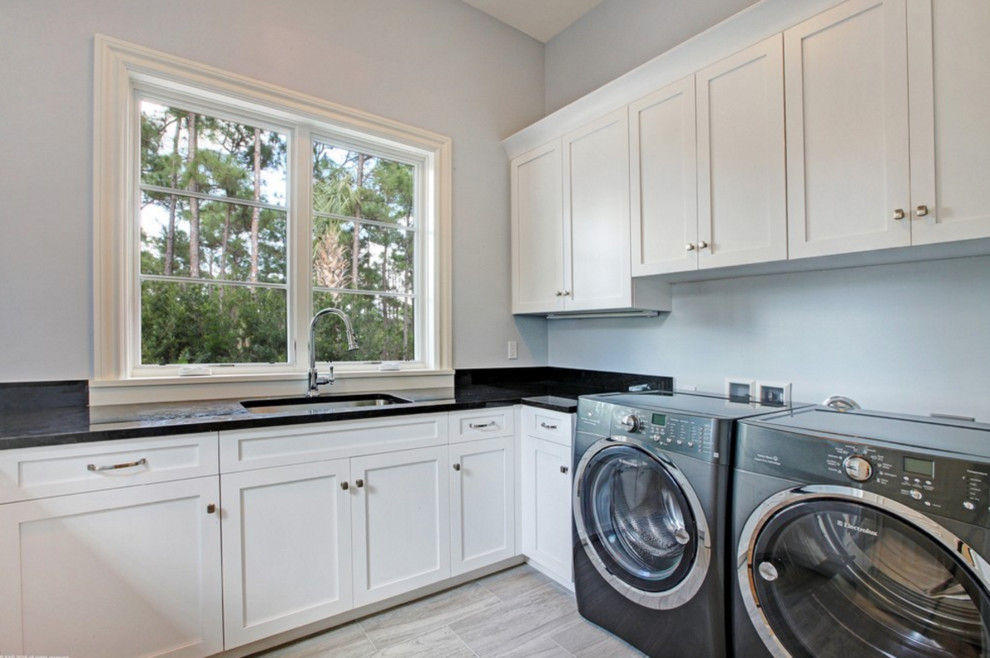 Design ideas for a large mediterranean l-shaped dedicated laundry room in Miami with an undermount sink, shaker cabinets, white cabinets, quartz benchtops, grey walls, porcelain floors and a side-by-side washer and dryer.
