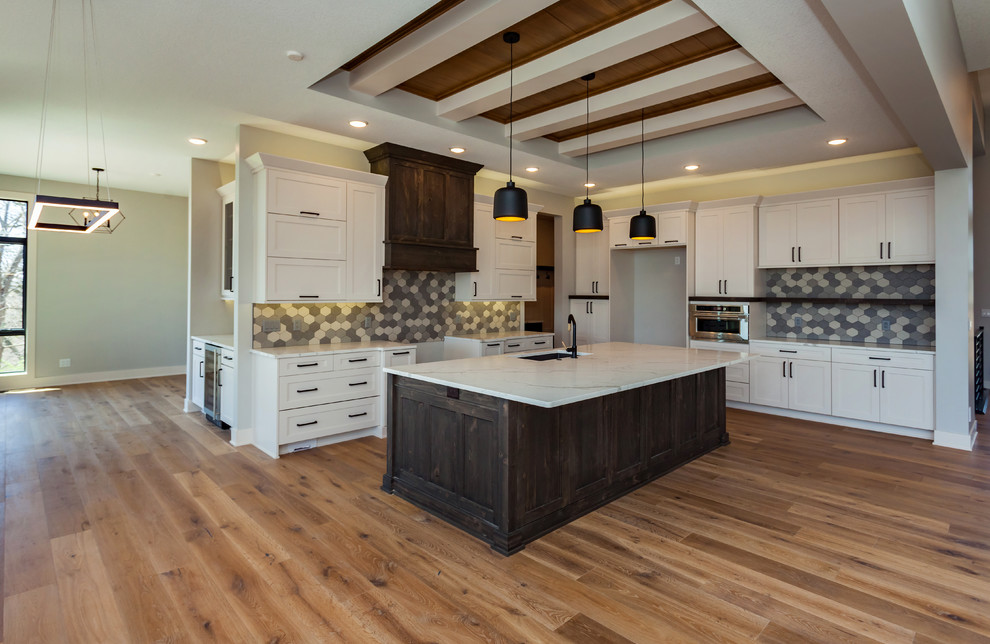 Example of a huge transitional l-shaped medium tone wood floor and brown floor open concept kitchen design with an undermount sink, shaker cabinets, white cabinets, marble countertops, multicolored backsplash, porcelain backsplash, stainless steel appliances, an island and white countertops