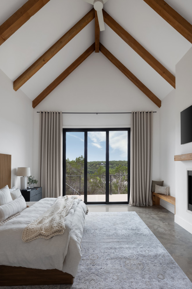 Ejemplo de dormitorio principal escandinavo grande con paredes blancas, suelo de cemento, chimenea lineal, marco de chimenea de yeso, suelo beige y vigas vistas