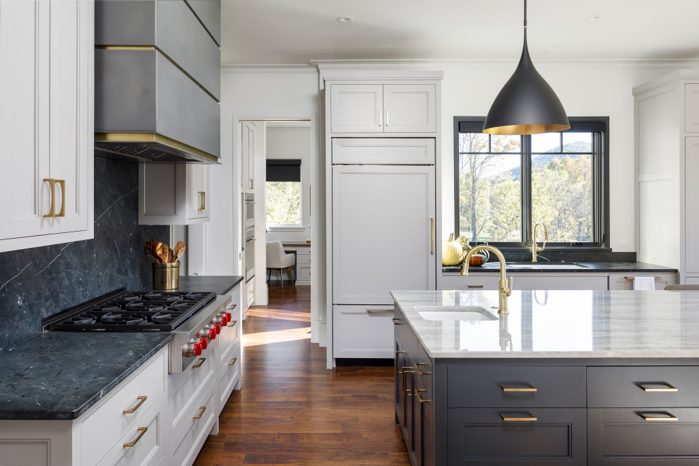 Exempel på ett mellanstort klassiskt flerfärgad flerfärgat kök och matrum, med en undermonterad diskho, luckor med profilerade fronter, vita skåp, bänkskiva i kvartsit, grått stänkskydd, svarta vitvaror, mellanmörkt trägolv, en köksö och brunt golv