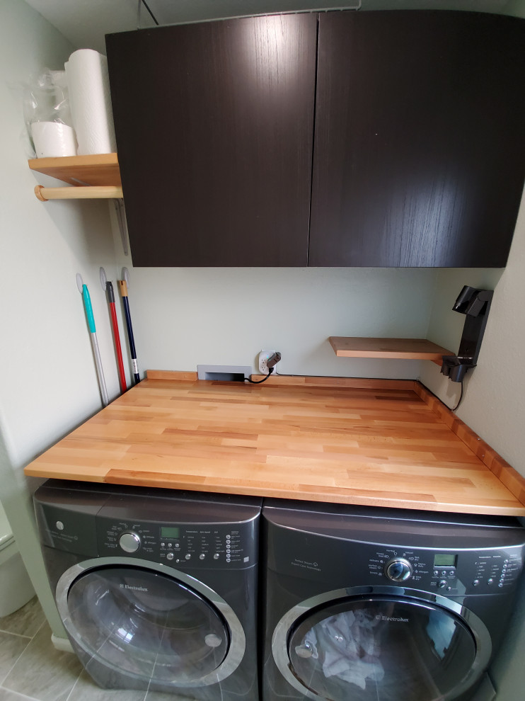 Design ideas for a small modern galley utility room in Denver with flat-panel cabinets, dark wood cabinets, wood benchtops, brown splashback, timber splashback, green walls, ceramic floors, a side-by-side washer and dryer, multi-coloured floor and brown benchtop.