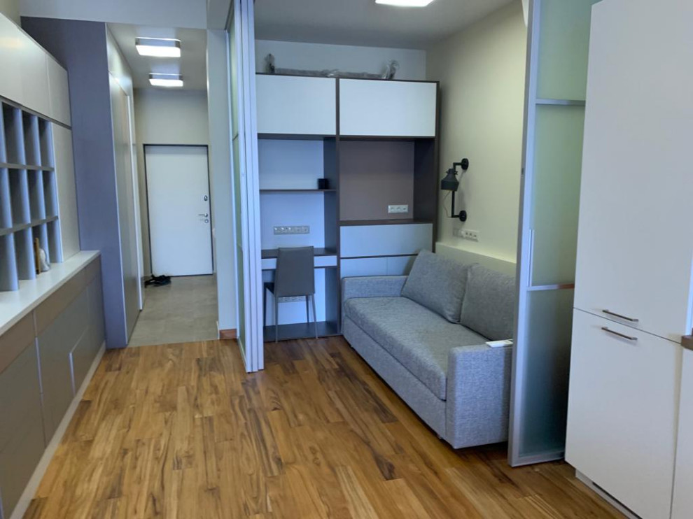 Imagen de despacho actual de tamaño medio con paredes beige, suelo de madera en tonos medios, escritorio empotrado, suelo beige y bandeja