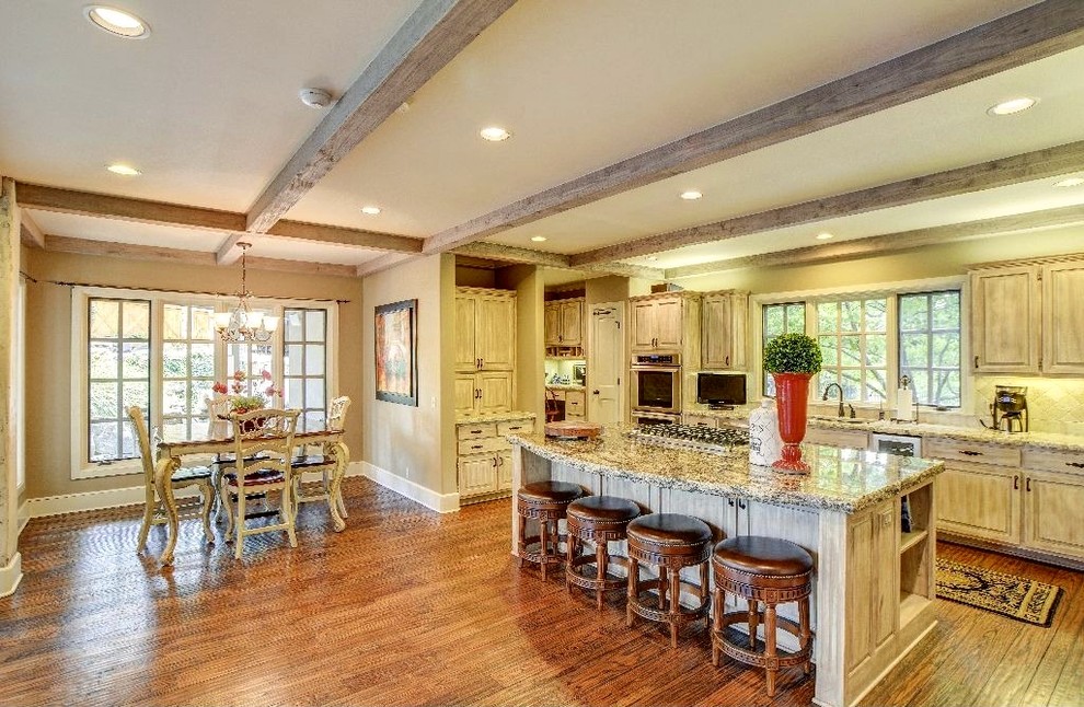 Large mountain style galley dark wood floor and brown floor eat-in kitchen photo with an undermount sink, raised-panel cabinets, distressed cabinets, granite countertops, beige backsplash, ceramic backsplash, stainless steel appliances and an island