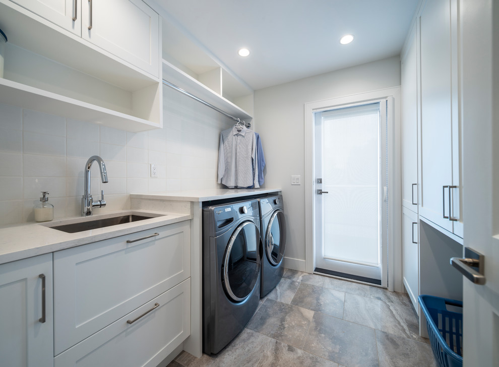 Photo of a mid-sized transitional galley dedicated laundry room in Vancouver with an undermount sink, shaker cabinets, white cabinets, quartz benchtops, red walls, porcelain floors, a side-by-side washer and dryer, grey floor and white benchtop.