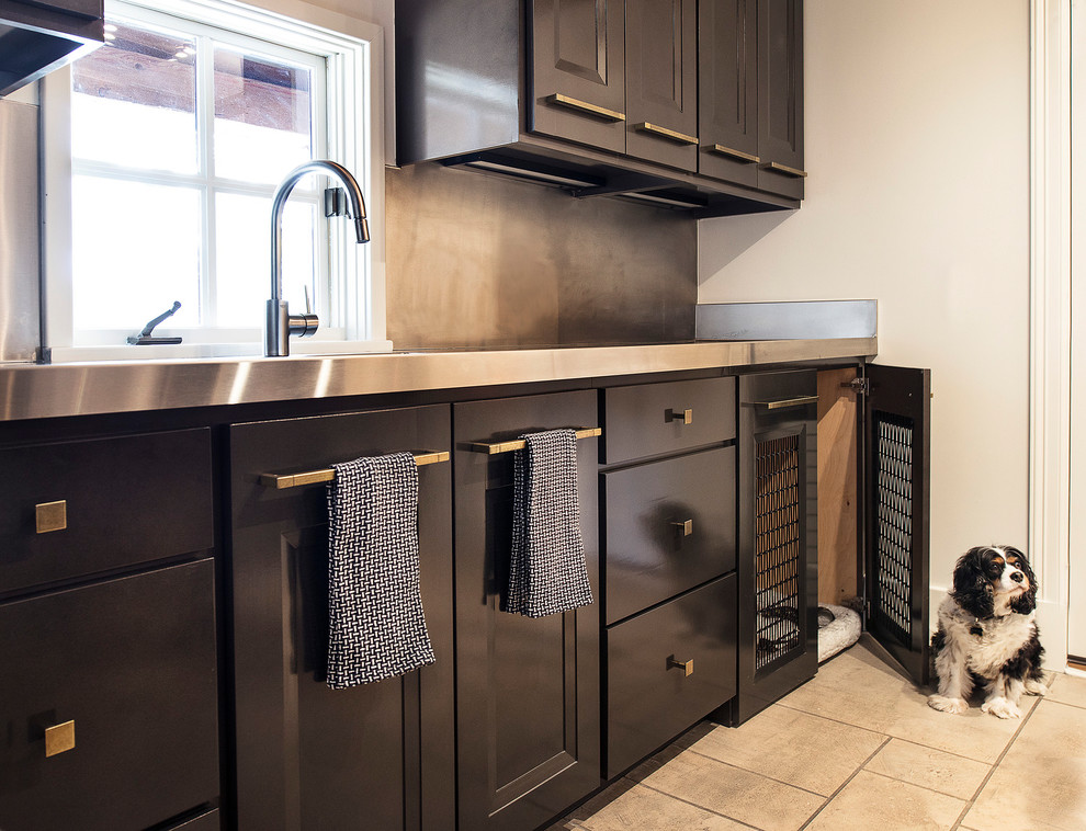 Photo of a large modern single-wall dedicated laundry room in Other with a farmhouse sink, brown cabinets, stainless steel benchtops and beige walls.