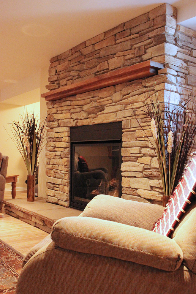 Inspiration for a large look-out basement in Ottawa with yellow walls, light hardwood floors, a standard fireplace and a stone fireplace surround.