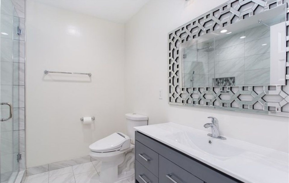 Inspiration for a small contemporary 3/4 bathroom in Orange County with flat-panel cabinets, grey cabinets, a corner shower, a two-piece toilet, gray tile, white tile, porcelain tile, white walls, porcelain floors, an integrated sink, engineered quartz benchtops, grey floor, a hinged shower door and white benchtops.