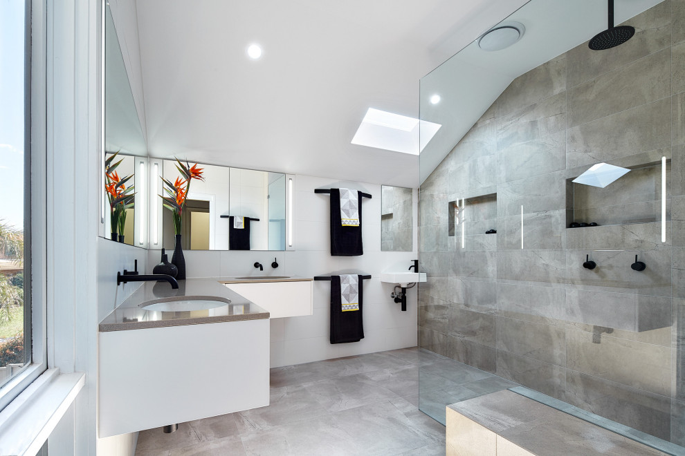 Contemporary bathroom in Melbourne with flat-panel cabinets, white cabinets, a curbless shower, gray tile, white walls, an undermount sink, grey floor, grey benchtops, a double vanity, a floating vanity and vaulted.