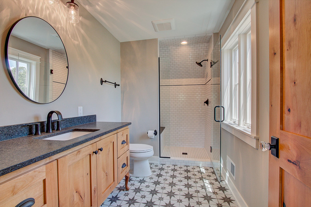 Photo of a large country kids bathroom in Milwaukee with flat-panel cabinets, light wood cabinets, a one-piece toilet, black and white tile, wood-look tile, beige walls, light hardwood floors, a vessel sink, granite benchtops, beige floor, a hinged shower door, black benchtops, a single vanity and a freestanding vanity.