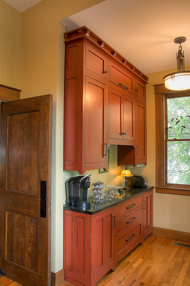 Photo of a small arts and crafts single-wall eat-in kitchen in Other with recessed-panel cabinets, medium wood cabinets, light hardwood floors and solid surface benchtops.