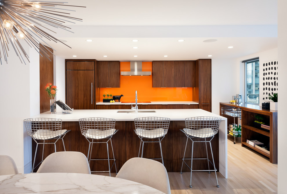 Photo of a contemporary galley eat-in kitchen in Seattle with an undermount sink, flat-panel cabinets, dark wood cabinets, orange splashback, glass sheet splashback, panelled appliances, light hardwood floors, a peninsula, beige floor and white benchtop.