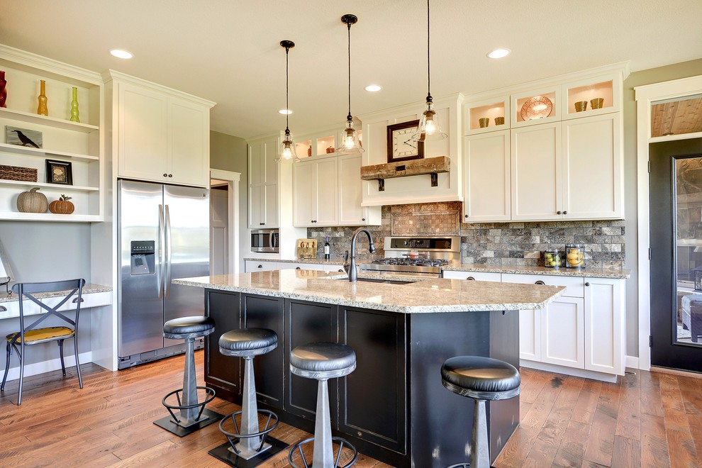 Transitional kitchen in Minneapolis with a double-bowl sink, shaker cabinets, white cabinets, multi-coloured splashback, subway tile splashback, stainless steel appliances, granite benchtops, medium hardwood floors, with island and brown floor.