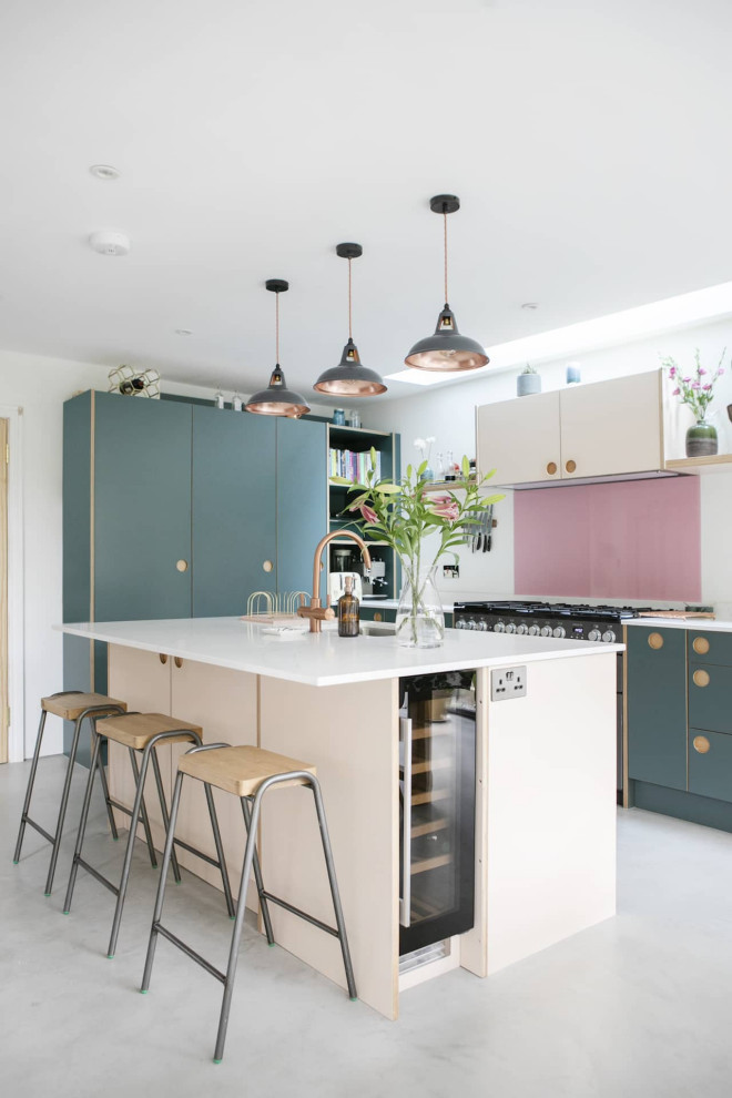 This is an example of a small contemporary single-wall open plan kitchen in London with an undermount sink, beaded inset cabinets, blue cabinets, quartzite benchtops, pink splashback, ceramic splashback, black appliances, ceramic floors, with island, grey floor, white benchtop and coffered.