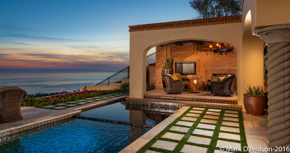 This is an example of a large mediterranean backyard rectangular lap pool in Los Angeles with a pool house and natural stone pavers.