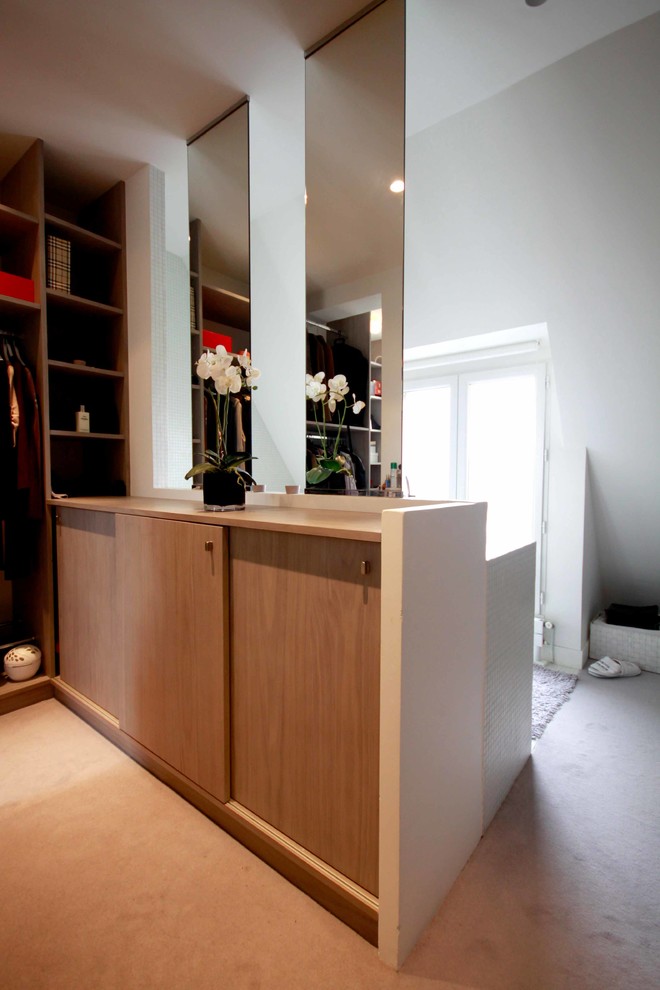This is an example of a small modern gender-neutral dressing room in Paris with open cabinets, grey cabinets and carpet.
