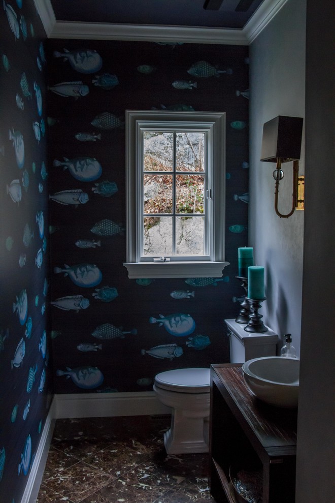 Inspiration för små maritima toaletter, med ett fristående handfat, möbel-liknande, skåp i mörkt trä, träbänkskiva, en toalettstol med separat cisternkåpa, blå väggar, marmorgolv, brun kakel och stenkakel
