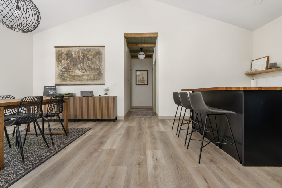 Ispirazione per una sala da pranzo aperta verso il soggiorno contemporanea di medie dimensioni con pareti bianche, pavimento in vinile, pavimento marrone e soffitto a volta