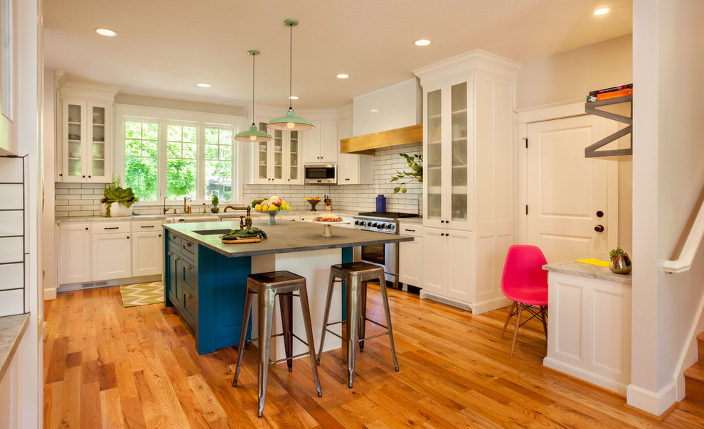 Large transitional u-shaped medium tone wood floor open concept kitchen photo in Portland with an island, a farmhouse sink, shaker cabinets, white cabinets, white backsplash, subway tile backsplash, stainless steel appliances and marble countertops