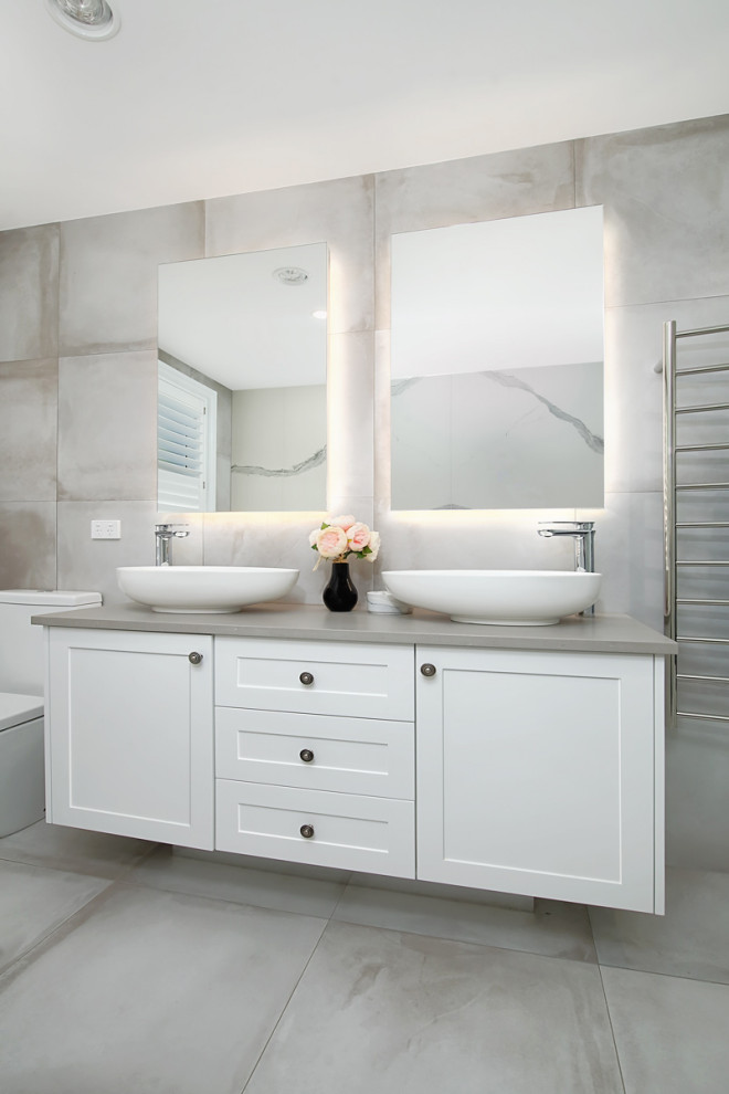 This is an example of a large beach style master bathroom in Sydney with shaker cabinets, white cabinets, gray tile, ceramic tile, ceramic floors, engineered quartz benchtops, grey floor, grey benchtops, a vessel sink and a double vanity.