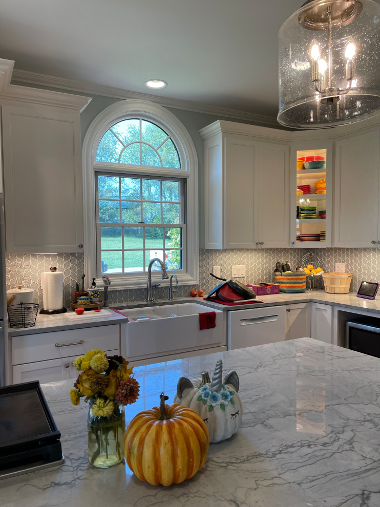 Large transitional light wood floor and brown floor eat-in kitchen photo with an undermount sink, shaker cabinets, white cabinets, quartzite countertops, green backsplash, marble backsplash, stainless steel appliances, an island and gray countertops