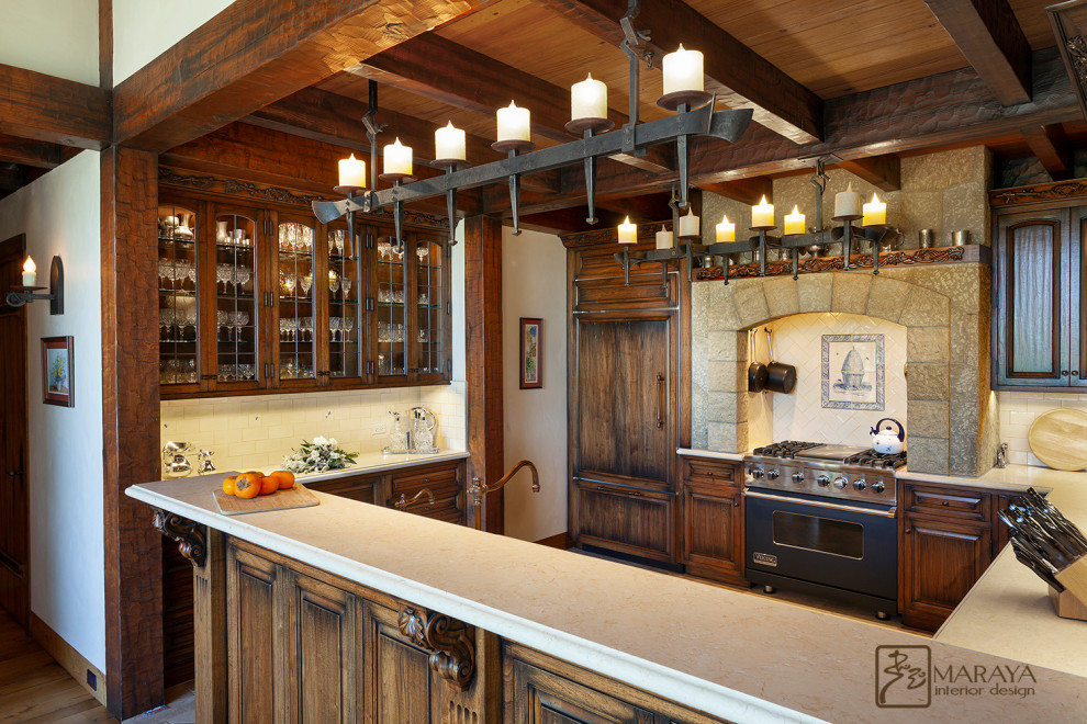 Photo of a mid-sized country u-shaped open plan kitchen in Santa Barbara with a farmhouse sink, raised-panel cabinets, distressed cabinets, quartzite benchtops, blue splashback, ceramic splashback, stainless steel appliances, dark hardwood floors, with island, brown floor and white benchtop.