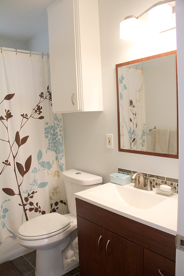 Стильный дизайн: маленькая главная ванная комната в современном стиле с плоскими фасадами, коричневыми фасадами, ванной в нише, душем над ванной, раздельным унитазом, зеленой плиткой, плиткой из листового стекла, синими стенами, полом из керамической плитки, монолитной раковиной, столешницей из искусственного камня, коричневым полом, шторкой для ванной, белой столешницей, тумбой под одну раковину и встроенной тумбой для на участке и в саду - последний тренд