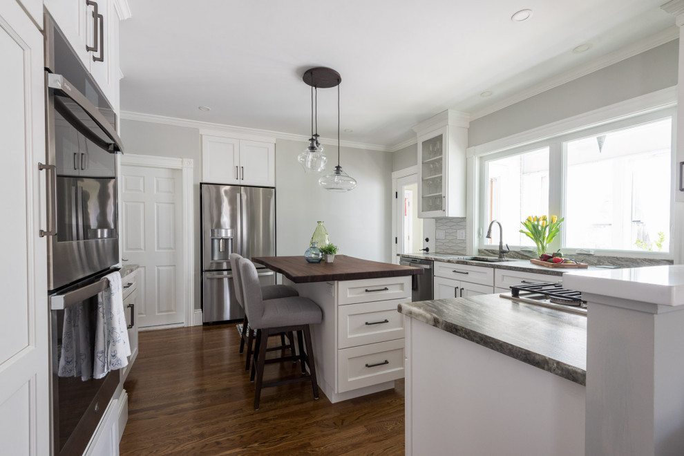 Example of a mid-sized transitional u-shaped medium tone wood floor and brown floor eat-in kitchen design in Boston with an undermount sink, shaker cabinets, white cabinets, quartzite countertops, gray backsplash, ceramic backsplash, stainless steel appliances, an island and multicolored countertops