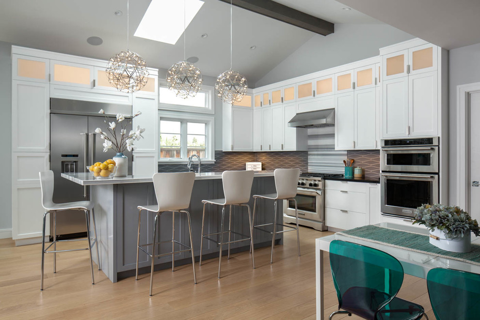 Inspiration for a transitional l-shaped light wood floor eat-in kitchen remodel in San Francisco with shaker cabinets, white cabinets, gray backsplash, stainless steel appliances, an island and black countertops