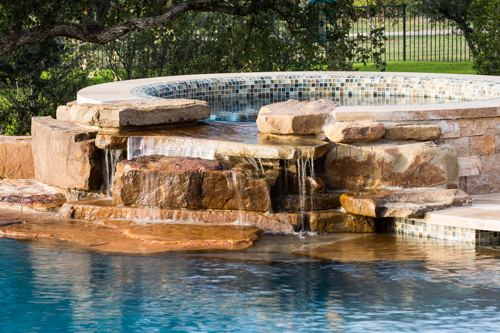 Design ideas for an expansive traditional backyard custom-shaped infinity pool in Austin with natural stone pavers.