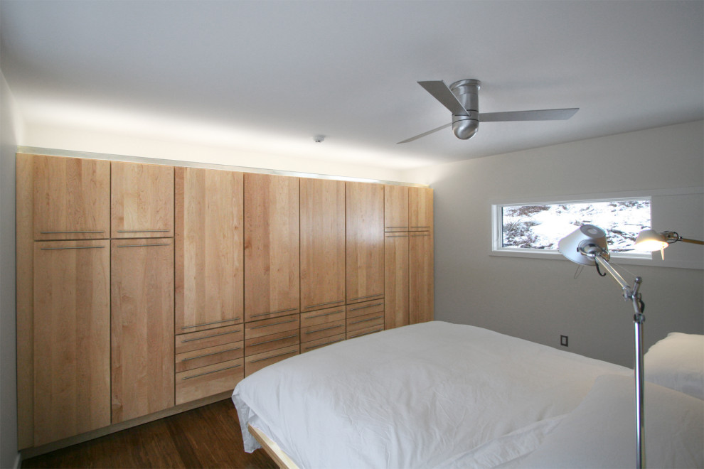 This is an example of a small contemporary loft-style bedroom in New York with white walls and medium hardwood floors.